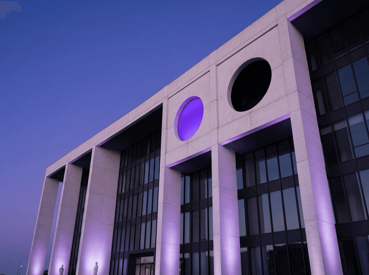 Fachada de prédio público institucional moderno com iluminação violeta ao entardecer