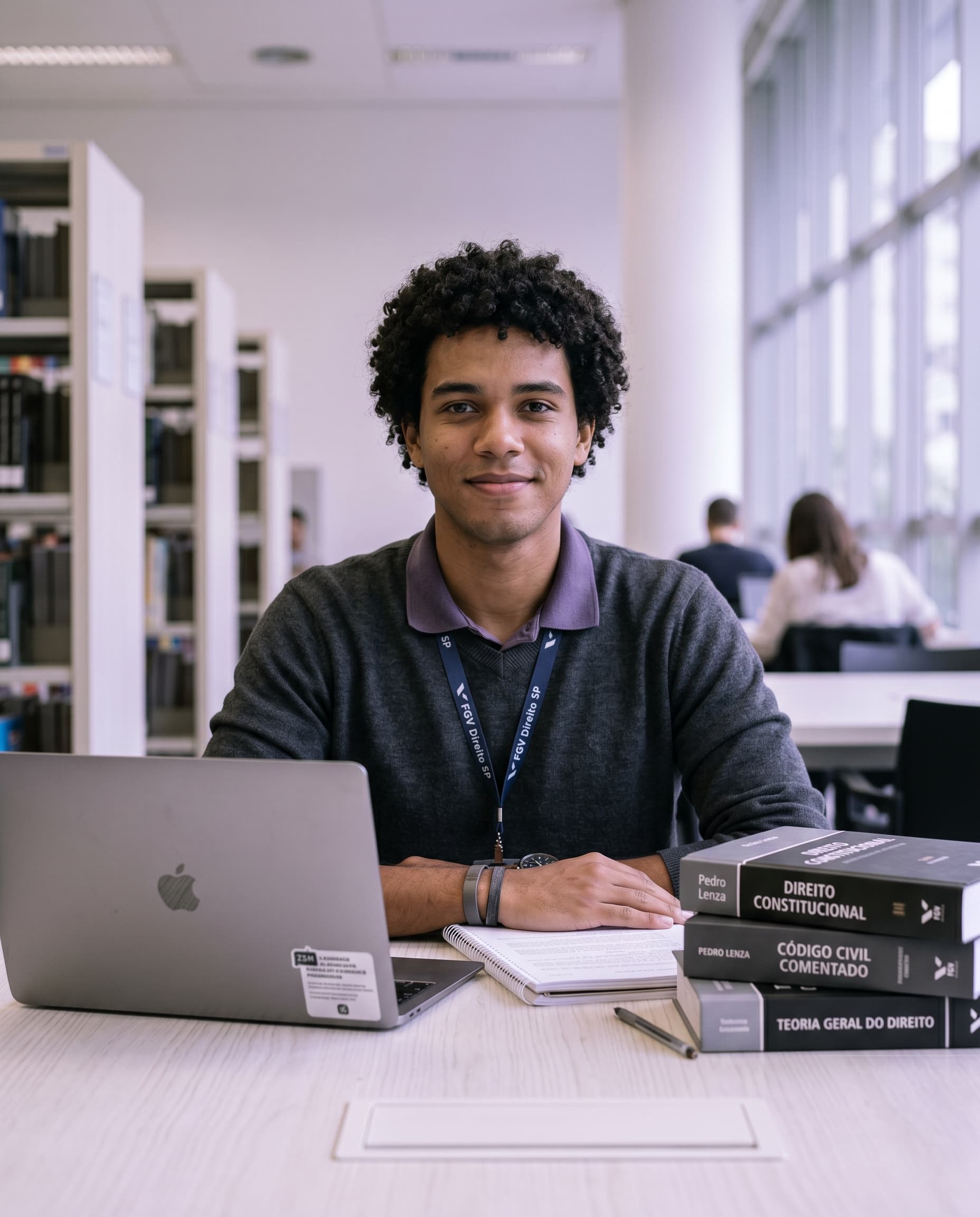 Estudante de Direito confiante estudando para concurso com livros de Direito Constitucional e notebook